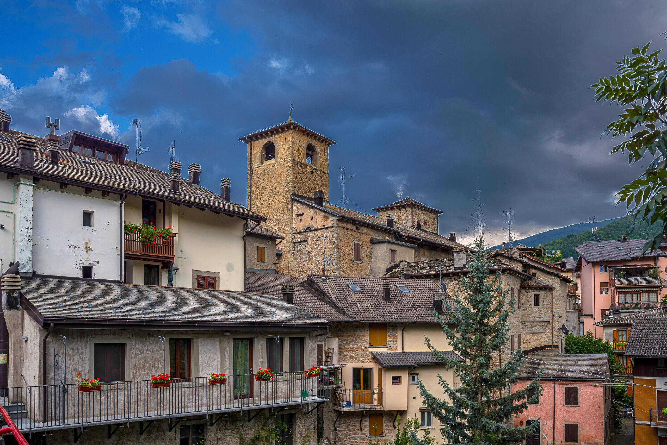 Case in pietra del centro storico di Fanano con la torre dell'orologio, sotto un cielo con nuvole