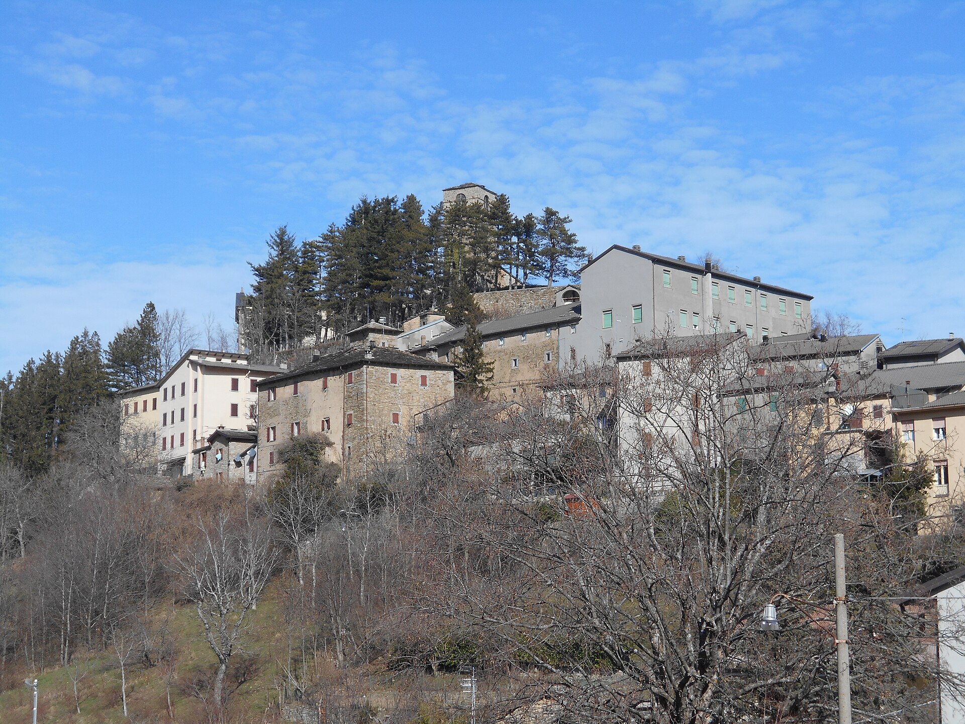 Le case in pietra di Montecreto arroccate sul colle, con il campanile e gli abeti alle spalle