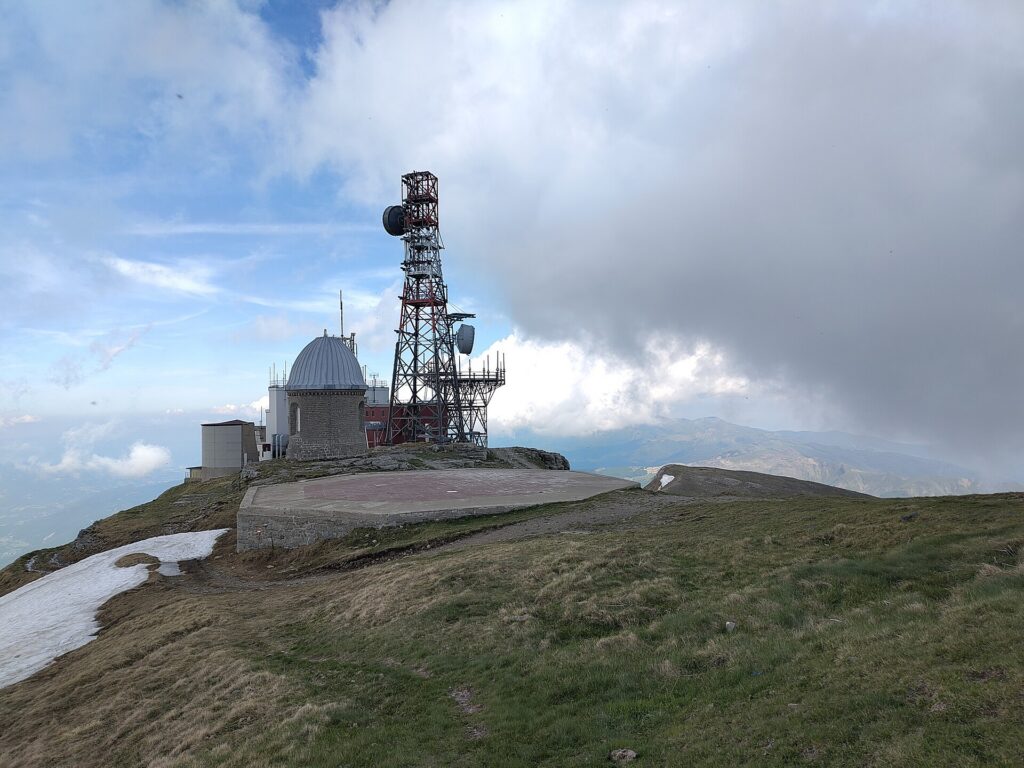 La cupola dell'osservatorio e il traliccio delle antenne sulla vetta del Monte Cimone, tra nuvole e cielo aperto