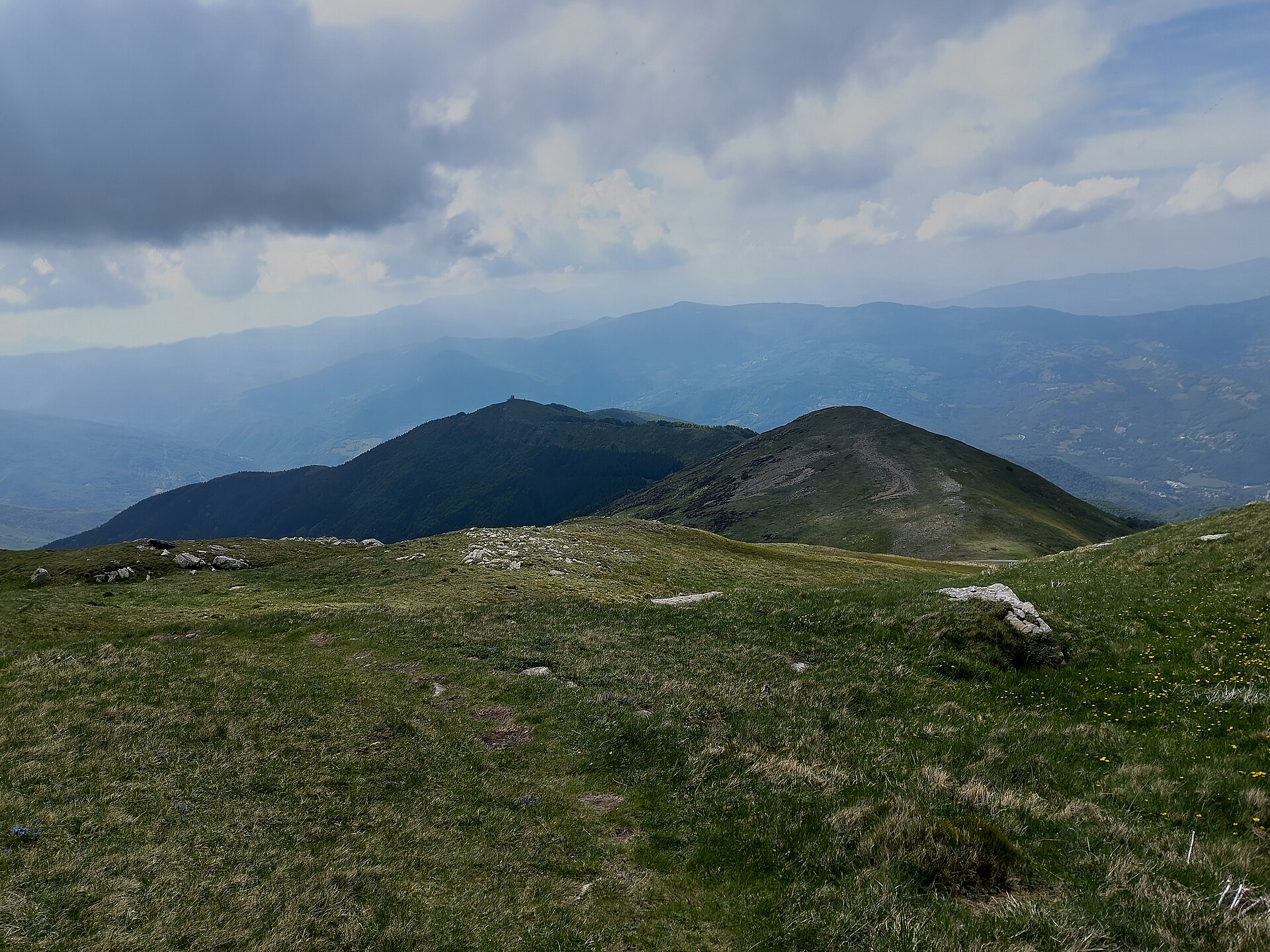 Praterie d'alta quota sulle pendici del Monte Cimone, con le creste dell'Appennino e il cielo nuvoloso